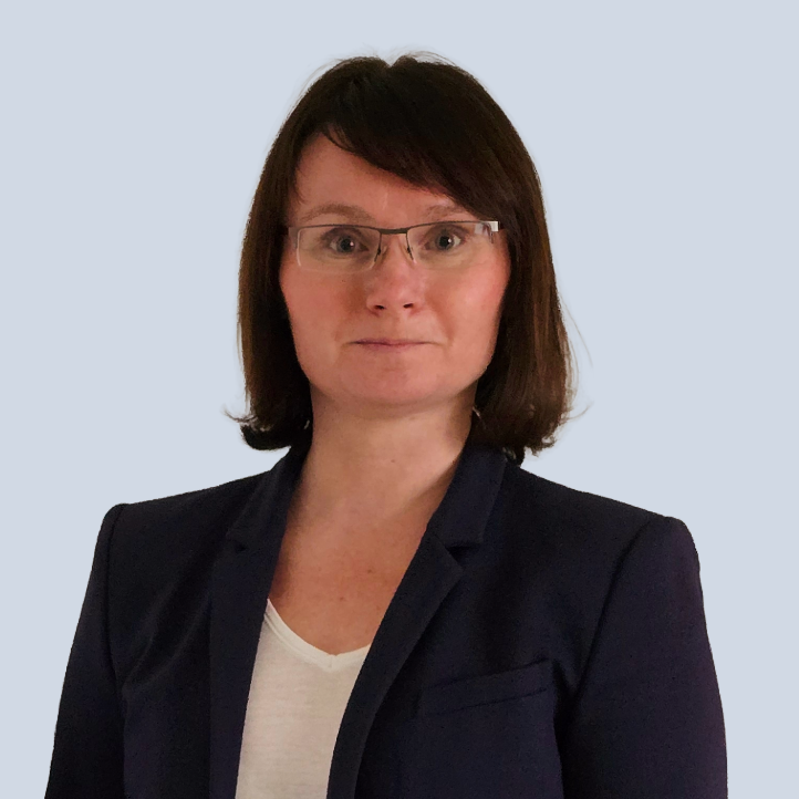 Frau Sok mit Brille, kurzen braunen Haaren und dunklem Blazer vor einem hellen Hintergrund.